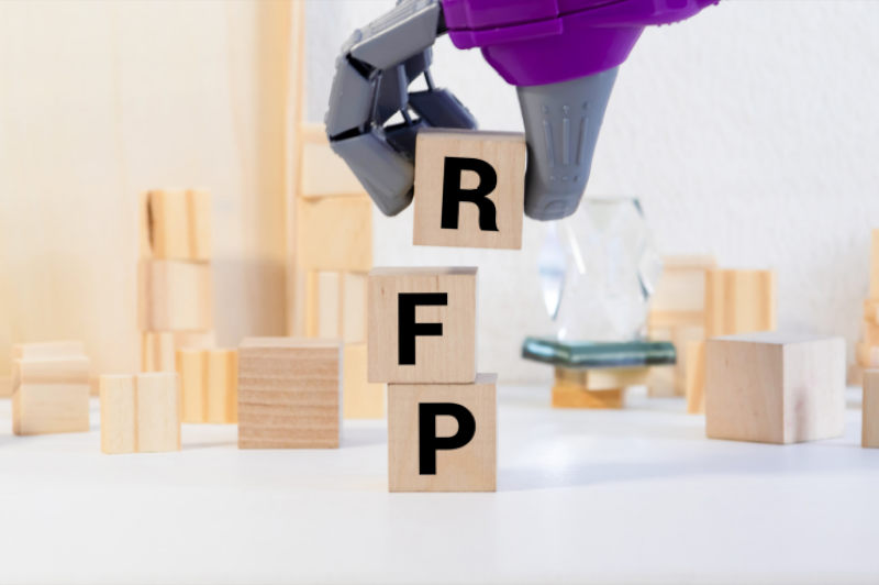 Robotic hand placing a wooden toy cube building block with the black letter R on to two other stacked blocks with letters F and P